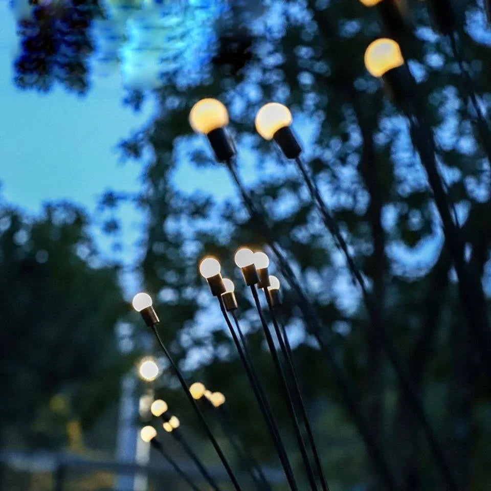 "Outdoor garden lights resembling glowing fireflies at dusk, with solar-powered warm LED bulbs atop slender stakes. Ideal for landscape decoration, these lights capture the ambiance of a serene twilight scene, adding a magical, whimsical charm to pathways, gardens, and backyard spaces.