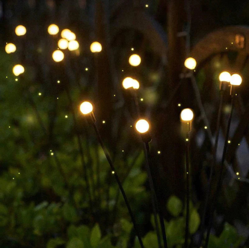 Enchanting firefly-inspired solar garden lights with soft, warm LED bulbs illuminating a nighttime garden setting. These ambient stake lights create a magical glow, blending with foliage to simulate the appearance of fireflies, perfect for adding a whimsical touch to pathways, flower beds, and outdoor landscapes.