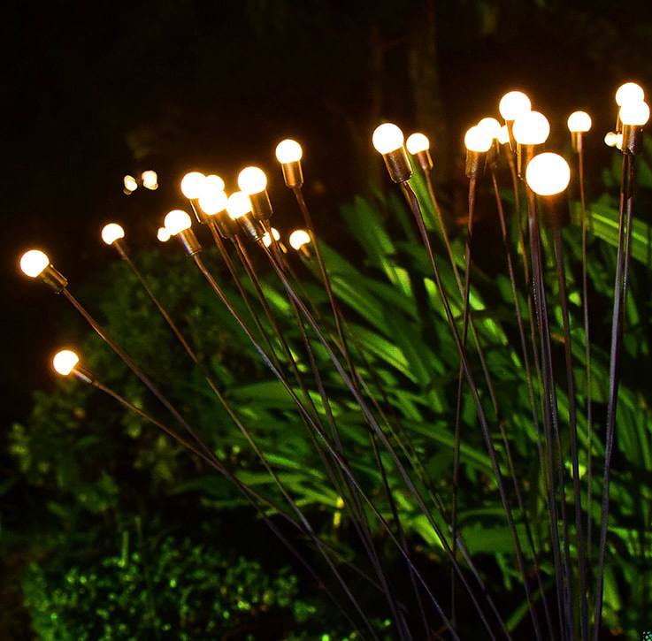 Solar-powered firefly garden lights with warm LED bulbs, delicately positioned in a lush outdoor setting to create a mesmerizing glow. These decorative stake lights mimic the charm of fireflies, perfect for adding magical ambiance to garden landscapes, pathways, and patios, transforming nighttime spaces into enchanting retreats.